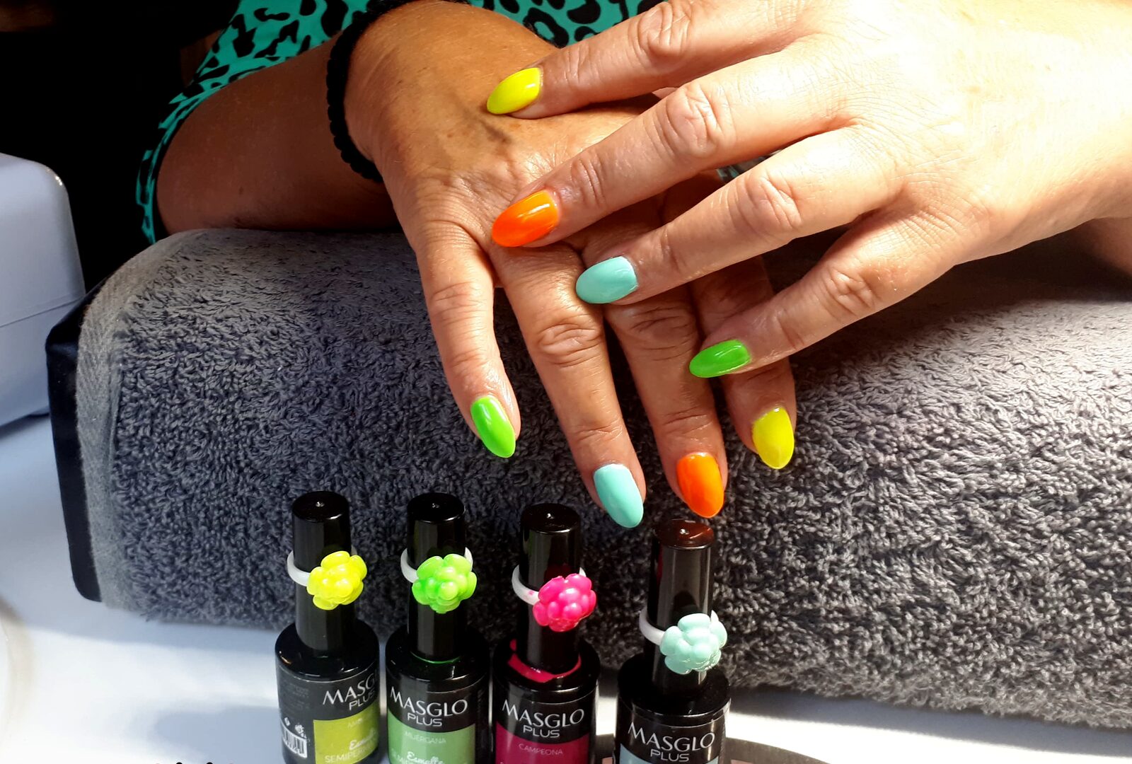 Nagels in neonkleuren gellak naast flesjes Masglo